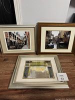 Three picture frames placed side by side, two frames show Venetian canal photographs, one brown wood and one silver-tone frame, the third shows weathered wall photo in a silver-tone frame.