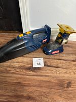 Photo of both Ryobi cordless tools side-by-side on floor showing Ryobi P710 Tuff Sucker wet/dry vacuum and Ryobi P600 laminate trimmer.
