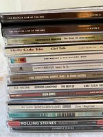 Stack of 15 CDs with visible spines showing artist and album titles, including Beatles, Rolling Stones, Bob Marley, Holly Cole Trio, Jimi Hendrix, Marvin Gaye, Gordon Lightfoot, Run DMC, Daryl Hall & John Oates, Barenaked Ladies, Stevie Ray Vaughan, and Great Big Sea.