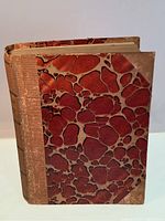 Front cover of the 1914 edition book showing cloth binding with marbled paper boards in reddish-brown and tan pattern, spine text faintly visible