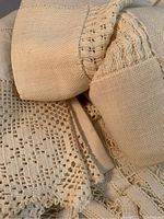 Close-up showing the weave and delicate lace detailing of one antique linen tablecloth in cream/off-white color.