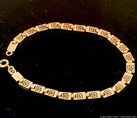 Full view of the sterling silver Greek key link bracelet laid flat on a dark surface.