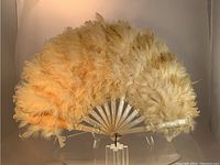 Full view of large pale yellow ostrich feather fan, showing overall shape and color