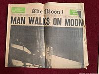 Front page of the vintage Vancouver Sun lunar supplement with large headline "MAN WALKS ON MOON" and partial image of lunar surface