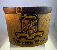 Front view of vintage Biltmore hatbox showing crest and graphic strap design