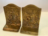 Front view of both brass bookends side by side showing blacksmith and horse scene with children watching.