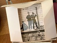 Close up photo showing one black and white photo of two armed soldiers standing near a wall inside a white paper folio