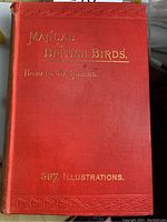 Front cover of the book 'Manual of British Birds' by Howard Saunders, red ornate hardcover with gold embossed text.