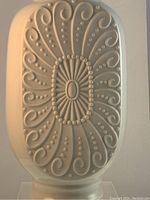 Close-up of the vase front showing the embossed geometric and ornate pattern with dots and swirls.