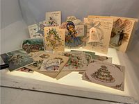 Photo showing the 22 vintage wedding greeting cards arranged for display. Various designs featuring flowers, bells, brides, and wedding themes visible.
