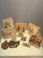 Collection of 10 vintage greeting and gift cards laid out showing variety of sizes and designs including floral, playful children, and holiday themes.