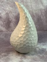 Front and side view of a white ceramic vase with a geometric, faceted surface and curved asymmetrical shape.