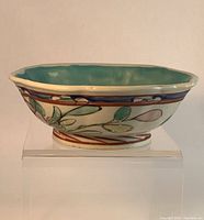 Side view of the ceramic footed bowl showing famille rose floral and bumblebee motifs and turquoise interior glaze.