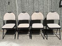 Front view of four matching folding chairs lined up against a textured wall.