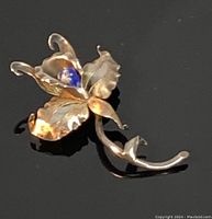 Front view of vintage silver orchid brooch featuring lapis lazuli stone and detailed etched and polished petals, showcasing craftsmanship and design.