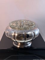 Silver plated rose bowl with a glass frog insert shown on a black surface from a front view.
