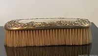 Full view of the antique sterling silver dressing brush showing natural bristles and detailed silver handle decoration.