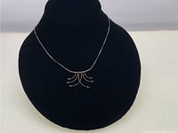 Front view of the sterling silver necklace displayed on a black velvet bust form, showing the chain and delicate modernist pendant clearly.