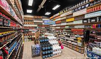 Photo shows the interior of a Popeye's Supplements store with shelves full of various sports nutrition products including protein powders, supplements, and shakers under bright lighting.