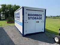 Front view of white and blue BoomBox Storage container showing double doors and logo