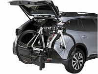 Front-side view showing rack mounted to 2″ hitch with two bikes installed and vehicle hatch open