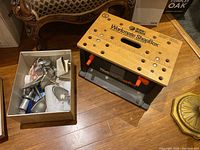 View showing Black and Decker Workmate ShopBox with wooden top and black base beside a white box containing various lighting parts.