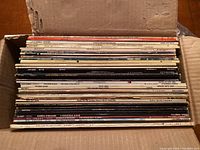 Photo of box filled with vinyl records stacked vertically showing album edges and spines.
