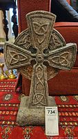 Front view of the man-made stone Celtic cross sculpture showing detailed carved knotwork patterns.