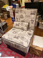 View of armchair showing Paris-themed printed fabric upholstery and matching pillow from a frontal angle.