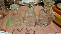 Photo showing three clear glass decanters arranged side by side, highlighting the intricate cut patterns and the different stopper styles.