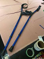 Pair of blue adjustable EZ Crutches lying flat showing forearm supports and grips.