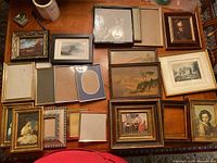 Overhead view of collection of picture frames and artworks on wooden surface showing various frame styles and sizes.