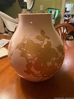 Photo of rounded beige ceramic vase with gold floral pattern, showing front side.