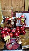Wide view showing red baubles and music instrument ornaments hanging on a dark wooden stand, plus a small house ornament and nutcracker fabric decoration.