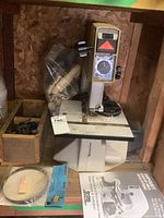 Full view of the beige-colored Shopcraft band saw with manual and accessories around it on a wooden shelf.