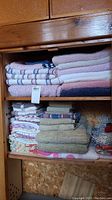 Overall view of wooden shelves containing stacks of bath towels, hand towels, dish towels, dish cloths, and placemats.