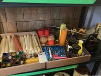 Box containing boxed and loose taper candles, pillar candles, a multicolored glass mosaic candle holder, assorted candle holders, and glass bottle lamp.