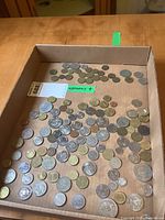 Top view of a cardboard box with many coins spread, mostly German coins visible