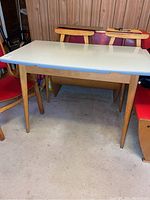 Full view of the rectangular dining table showing the white Formica top and tapered wooden legs.