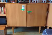 Front view of two-door wooden cabinet on tapered legs