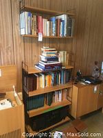 Photo of a freestanding metal and wood bookshelf filled with assorted books, audio stereo at the bottom shelf