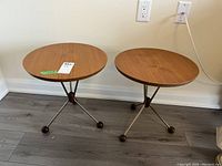 Two round side tables side by side on floor against wall