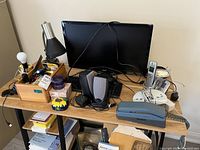 General view of office lot with computer monitor, desk lamp, speakers, desktop telephones, wood organizer with supplies on desk.
