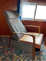 Side three-quarter view showing teak wood frame, slatted wooden seat, grey upholstered backrest, reclined position