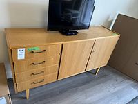 Full side view of the wooden sideboard showing four drawers on left and cupboard doors on right with a TV on top.