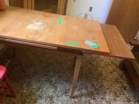 Overall view of teak table with one extension leaf partially inserted