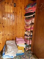 Stacked folded towels against wood-paneled wall showing beige, blue, and various other colored towels