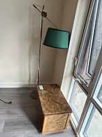 Floor lamp next to handcrafted wooden chest with visible detailed wood pattern and metal studs