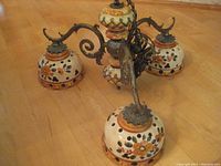 View of antique ceramic light fixture showing four floral painted shades and metal embossed chain link structure