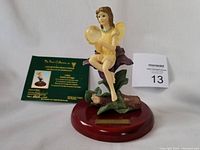 Full view of the Bubble of Magic fairy figurine seated on a flower on wooden base, with certificate and lot number tag.